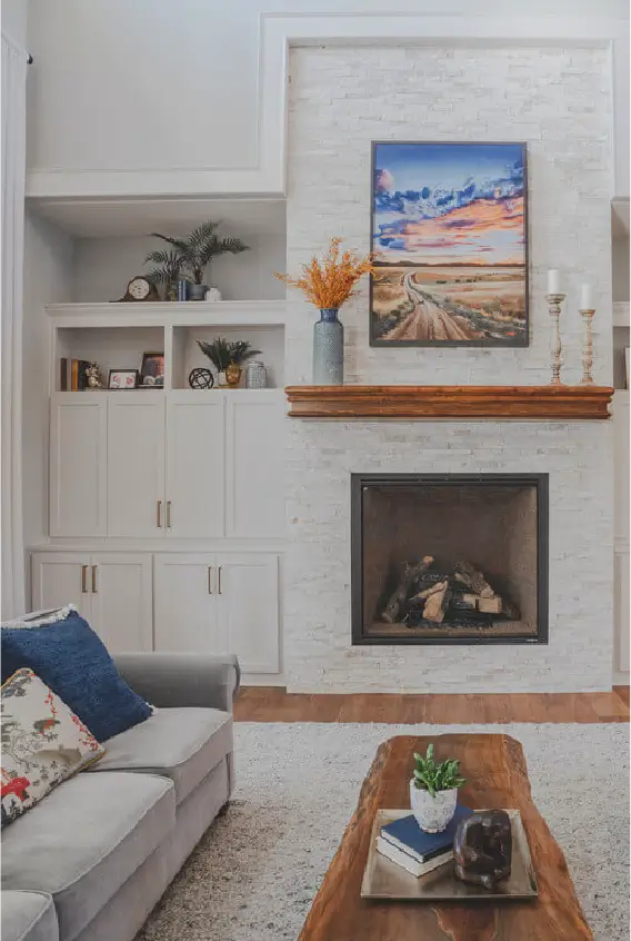 warm living room with wood tones, white fireplace, and colorful art displayed